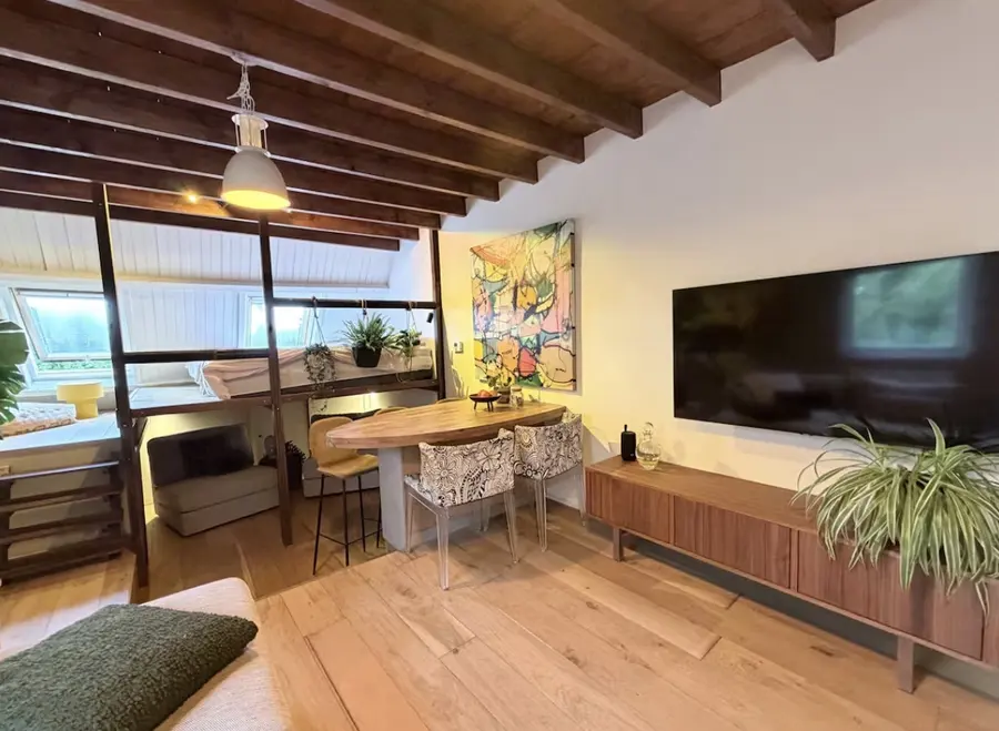 Binnen in de BnB: eettafel, slaapzolder en een houten balkenplafond